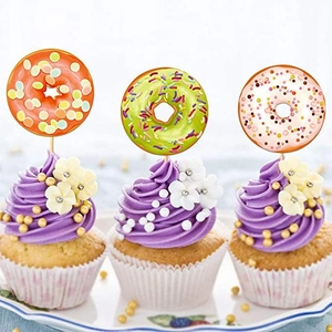Close-up of three donut cupcake toppers in orange green and pink on purple frosting