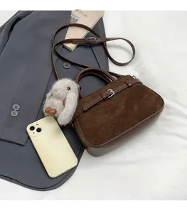 Détail du sac à main en cuir marron foncé avec boucle argentée et breloque en lapin