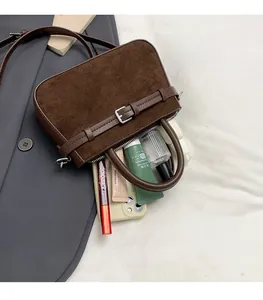 Détail d'un sac à main en daim marron offrant un grand espace pour cosmétiques et mobile