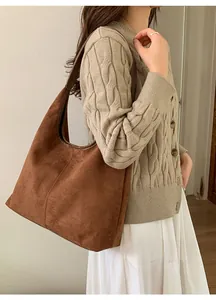 Détail d'un grand sac hobo marron mat porté avec un pull en maille beige chic pour femme