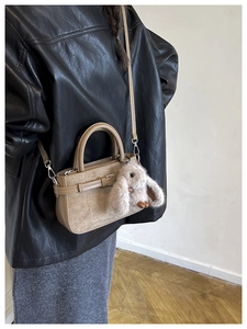 Sac bandoulière kaki avec boucle et breloque lapin en peluche porté par un mannequin