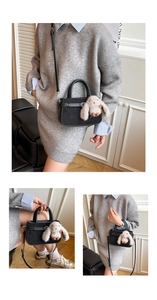 Détail du sac à main en daim noir avec breloque lapin en peluche et bandoulière réglable