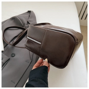 Macro shot of dark brown soft leather handbag showing bottom stitching and silver zipper detail