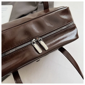 Detail of dark brown faux leather bag with smooth double metal zipper closure