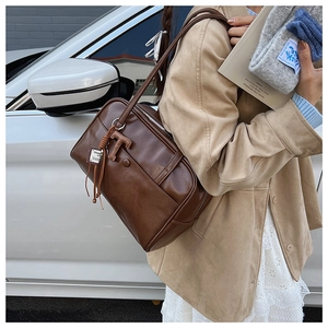 Close-up of vintage brown leather shoulder bag with T-shaped charm and fashion tag