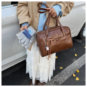 Detail of vintage brown leather handbag with T-pendant and grey knit gloves in autumn scene