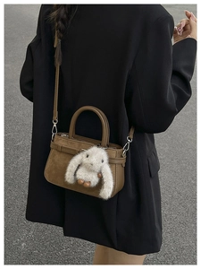 Sac bandoulière en daim marron avec breloque lapin en peluche porté par un mannequin