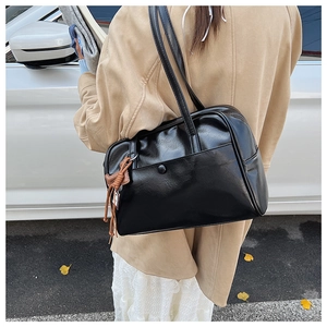 Side view of a vintage large black leather shoulder bag with decorative brown tassel