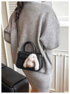 Détail d'un sac bandoulière classique noir avec un pendentif lapin en peluche doux