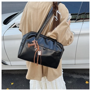 Close-up of minimalist black faux leather tote bag featuring a leather T-letter charm