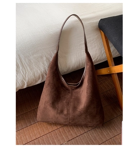 Détail macro du sac cabas en daim marron foncé avec couture verticale et texture mate