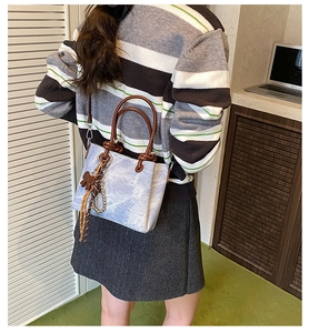 Detail of light blue marble pattern handbag with brown handle and pearl tassel charm