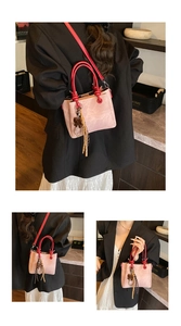 Detail of pink vintage bucket bag with red contrast handles and leather bow charms