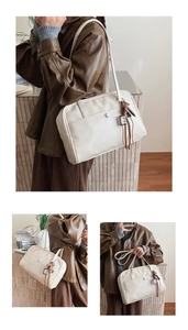 Detail of white large capacity tote bag featuring decorative button and tassel charm