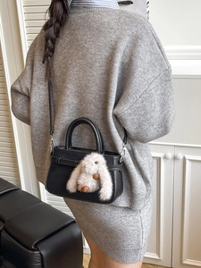 Sac bandoulière en cuir noir mat avec pendentif lapin en peluche sur tenue en tricot