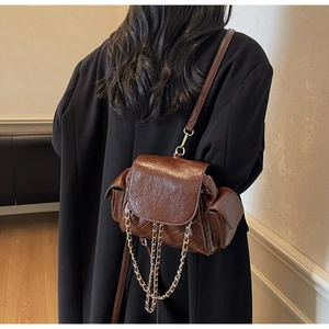 Detail of vintage brown quilted shoulder bag with metal chain on black wool coat