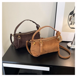 Detail of vintage suede cylinder bags with golden hardware and adjustable straps
