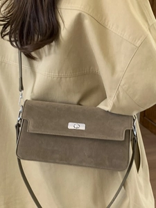 Vintage dark brown suede shoulder bag with silver turn-lock and slim strap on model