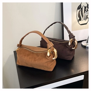 Close-up of matte suede cylinder handbags with vintage gold chain detail and leather handle