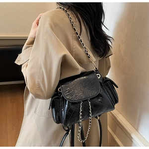Close-up of quilted black oil wax leather backpack with golden chain strap and side pocket