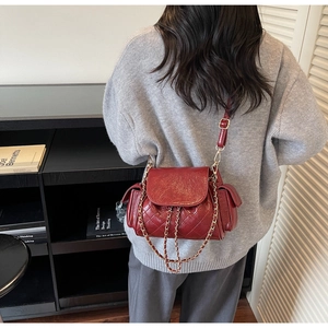 Detail of red quilted faux leather shoulder bag with gold chain and side pockets