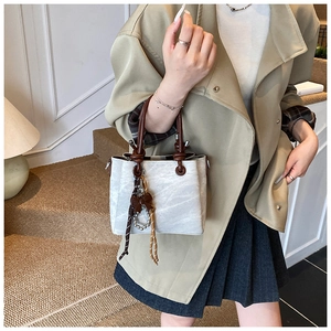 Detail of white marble pattern handbag with brown leather handle and pearl tassel charm
