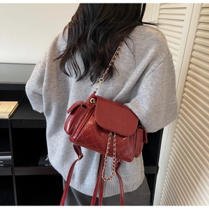 Detail of burgundy quilted faux leather backpack with gold chain straps and glossy finish