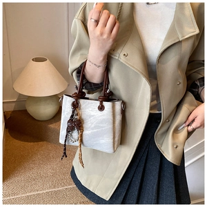 Detail of retro stone pattern handbag with brown bow charm and metallic D-ring buckle