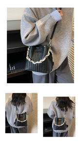 Detailed view of black woven bucket bag featuring silk scarf handle and gold chain strap