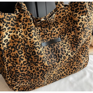 Detail view of the front pocket and canvas leopard print texture on the large tote bag