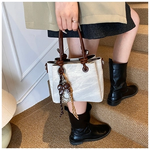 Detail of cream bucket bag featuring a marble texture and brown knotted leather handles