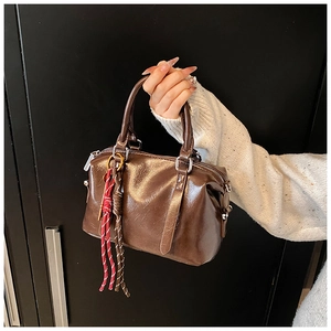 Close-up of glossy brown retro handbag with silver hardware and braided rope detail