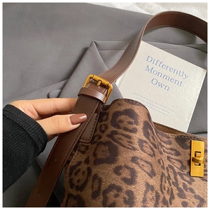 Macro view of leopard print shoulder bag with brown leather strap and golden buckle details