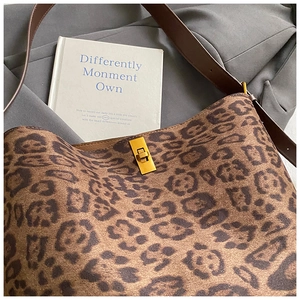 Detail of leopard print handbag with brown leather strap and golden twist lock closure
