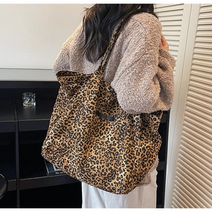 Close-up of large leopard print tote bag with black leather side detail on a model