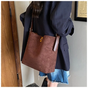 Brown faux suede tote bag with leather strap and gold buckle shown on a model