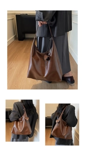 Detail of dark brown polished leather hobo bag showing high-gloss texture and gold lettering
