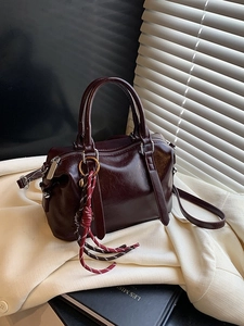 Bordeaux red vintage Boston handbag with dual handles and woven tassel charm