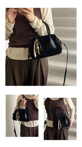 Detail view of black suede crossbody bag with colorful wooden bead charm and thin strap