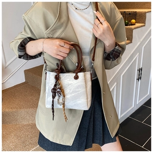 Close-up of marble pattern bucket bag with brown handles and decorative silk scarf