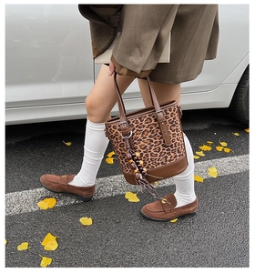 Detail of leopard print bucket bag with brown leather handles and beaded tassel charm