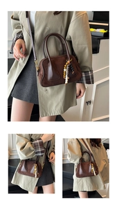Detail of a brown suede handbag showing the dark brown triangle patch and wood bead charm