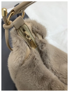 Détail du sac fourre-tout en fausse fourrure beige avec zip doré et attache en cuir