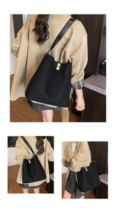 Detail of a large black suede tote bag featuring a premium gold twist lock closure
