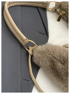 Vue détaillée de la texture pelucheuse et de l'anneau en métal doré du sac couleur kaki