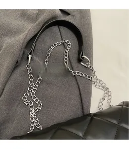 Detail view of black quilted crossbody bag with silver chain and wide leather strap