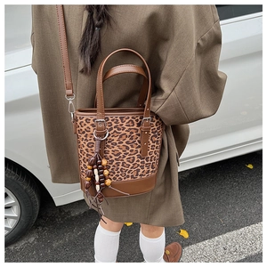 Detail of leopard print bucket bag featuring brown leather trim and ethnic bead charm