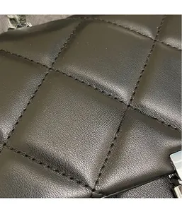 Close-up of black quilted leather texture and silver chain strap detail on a handbag