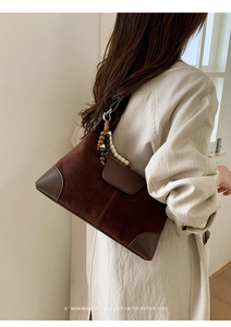 Detail of retro dark brown suede handbag with wood beads charm on a trench coat
