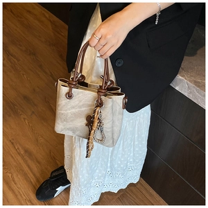 Detail of vintage stone-textured mini bucket bag with dark brown circular handles and scarf